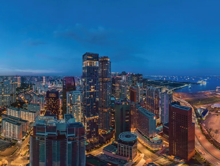 Newport Residences, photograph for illustration only: the towers of Tanjong Pagar and the city lit at dusk, seen from height, with the waterfront on the right