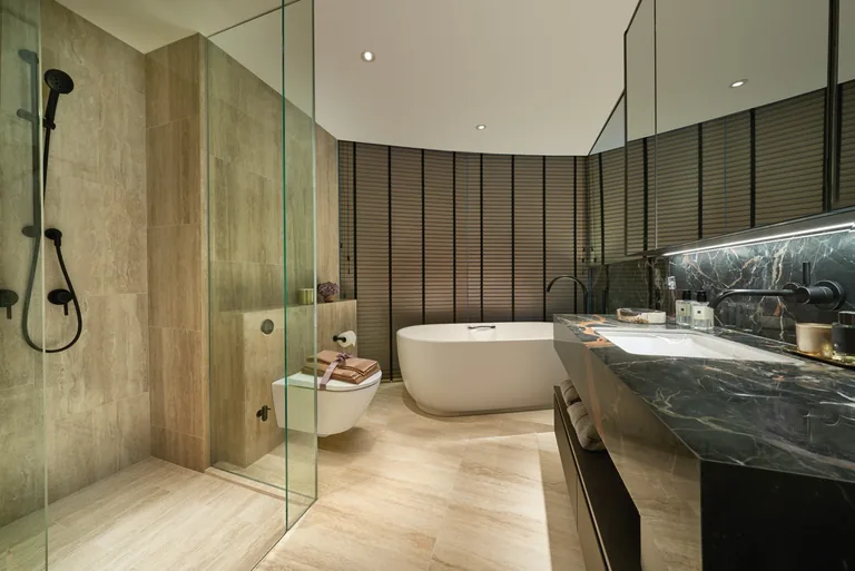 Newport Residences, interior photograph for illustration only: a master bath with a freestanding tub, a rain shower behind glass and a dark marble vanity